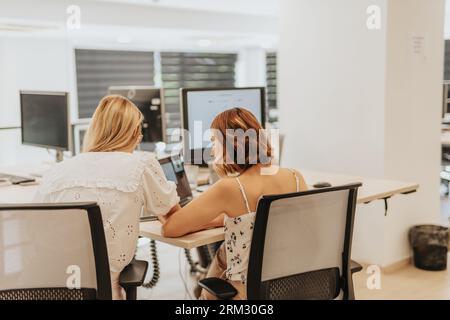 Team of two female colleagues working together in an office, analyzing data and collaborating on innovative strategies for business growth. Stock Photo