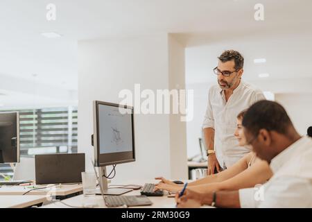 Collaborative business team analyzing statistics and discussing profit growth in a modern, diverse office environment. Senior businessman supervising Stock Photo