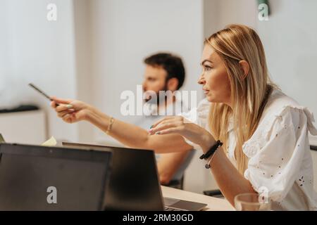 A diverse team of business professionals analyzing statistics and discussing project development in an office workspace. Effective communication and t Stock Photo