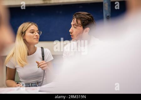 Students sharing knowledge gathered at table in the college yard Stock Photo