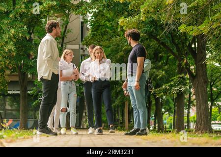 Group of young and well-dressed students standing outside and talking Stock Photo