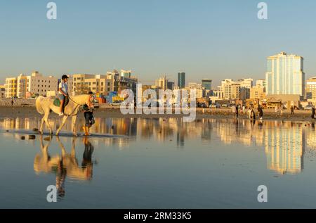 Horse riding led by a man at the Karbabad beach. Seef Bahrain Stock Photo