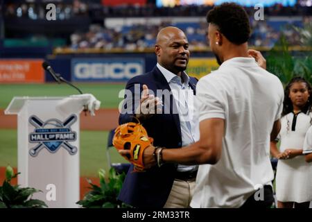 Former Tampa Bay Rays player Carl Crawford, center, embraces his son  Justin, front right, after throwing out a ceremonial first pitch during his  Rays Hall of Fame induction ceremony prior to a