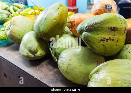 Green coconuts are on a counter at local marketplace, Seychelles Stock Photo