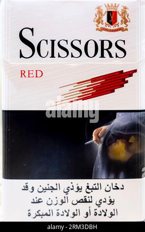 Scissors red cigarettes pack arabic edition showing pregnant woman in hijab smoking with warning Stock Photo