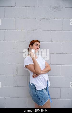 Happy young ethnic woman standing near brick wall with credit card Stock Photo