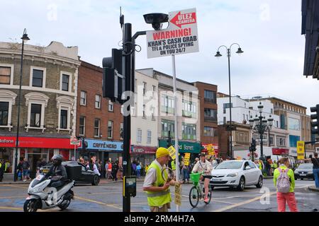 London, UK. 26th August, 2023. Protesters hold up a sign warning passing motorists of a ULEZ camera overhead. Anti-ULEZ protesters gather in the Mayor of London's constituency in Tooting, ahead of the air pollution scheme expanding and becoming effective on Tuesday 29th. Demonstrators object to the charges being implemented to clean up the Capital's air, believing it to be no more than a way to tax motorists and hitting the poorest in society the hardest. Credit: Eleventh Hour Photography/Alamy Live News Stock Photo