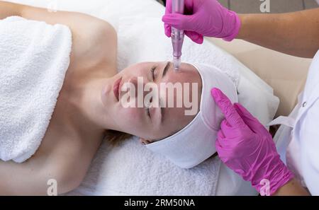Top View Cosmetologist Doing Mesotherapy Injection With Dermapen On Face Of Young Woman For Rejuvenation In Spa Center. Patient Getting Needle Stock Photo
