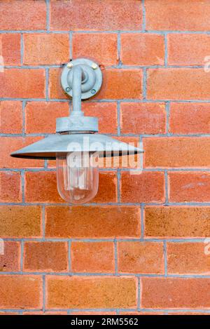 An older style outdoor or outside light mounted on a brick wall in Sydney, Australia with a tin hat style shade to reduce upward spread of light Stock Photo