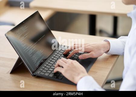 Asian programmer writing code on a laptop Stock Photo