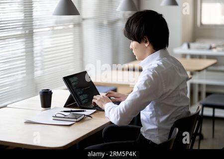 Asian programmer writing code on a laptop Stock Photo