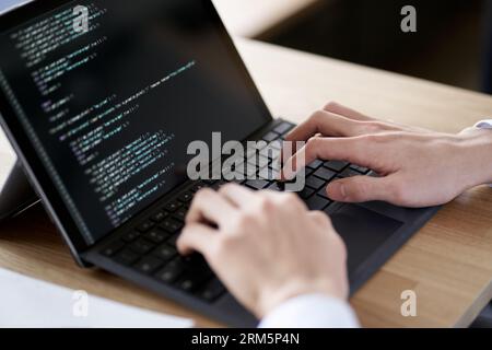 Asian programmer writing code on a laptop Stock Photo