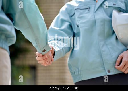 Construction worker shaking hands in front of the building Stock Photo