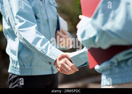 Construction worker shaking hands in front of the building Stock Photo