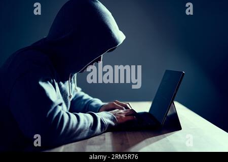 Male hacker writing code on a laptop Stock Photo
