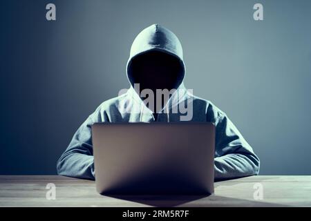 Male hacker writing code on a laptop Stock Photo