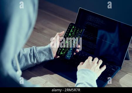 A male hacker checking the operation on a smartphone Stock Photo