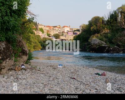 Pebbled beach along the banks of the Neretva River with Mostar old town behind, Bosnia and Herzegovina, August 26, 2023. Stock Photo