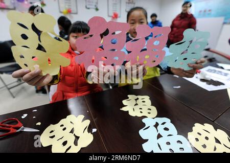 (140122) -- HANGZHOU, Jan. 22, 2014 (Xinhua) -- Pang Yanan (L), an 11-year old girl, shows her paper-cutting works of Chinese character reading Fu , which means happiness, to greet the upcoming Spring Festival in Hangzhou City, capital of east China s Zhejiang Province, Jan. 22, 2014. The Spring Festival falls on Jan. 31 this year. (Xinhua/Ju Huanzong) (ry) CHINA-HANGZHOU-SPRING FESTIVAL-CUSTOM (CN) PUBLICATIONxNOTxINxCHN   Hangzhou Jan 22 2014 XINHUA Pang Yanan l to 11 Year Old Girl Shows her Paper Cutting Works of Chinese Character Reading Fu Which Means HAPPINESS to Greet The upcoming Sprin Stock Photo