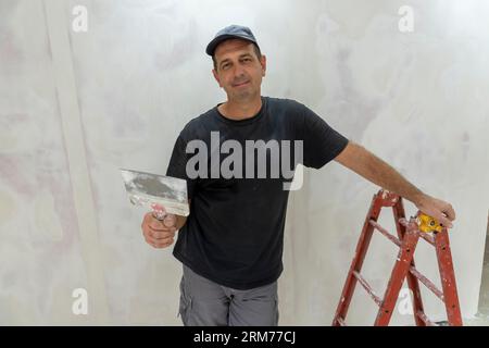 Male builder, master office, plasterer with a tool in working clothes Stock Photo