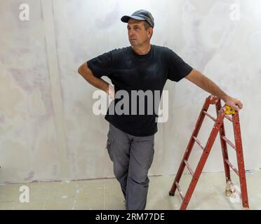 Male builder, master office, plasterer with a tool in working clothes Stock Photo