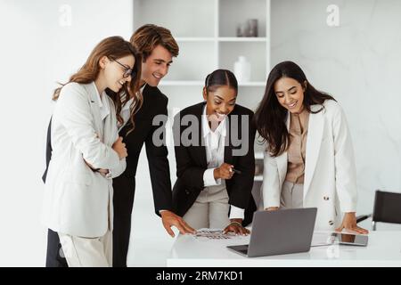 International business colleagues using laptop, working on project and discussing business targets in office Stock Photo