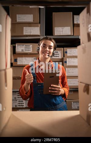 Warehouse inventory manager using digital tablet showing thumbs up gesture while looking at camera Stock Photo