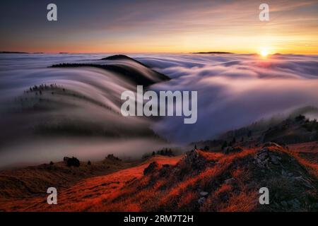 Mountains in fog at beautiful sunset in autumn in Slovakia Landscape with alpine mountain valley, low clouds, forest, purple sky city illumination at Stock Photo