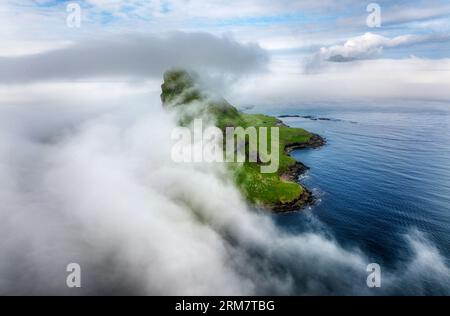 Faroe islands landscape from drone, big cliff and ocean with many clouds. Tindholmur on Faroe Islands Vagar Stock Photo