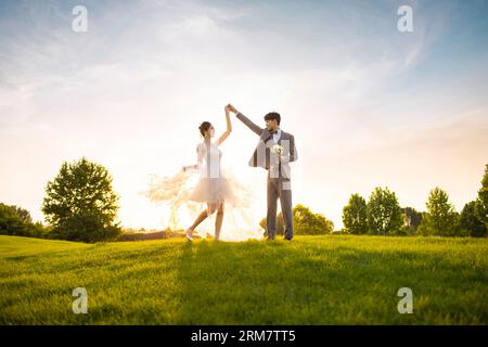 Happy bride and groom dancing on the grass Stock Photo