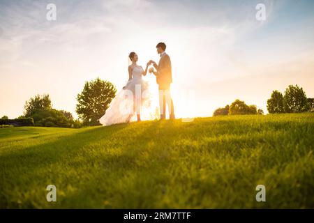 Happy bride and groom dancing on the grass Stock Photo