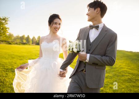 Happy bride and groom walking on the grass Stock Photo