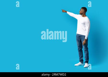 Handsome black guy pointing at copy space, touching something invisible Stock Photo