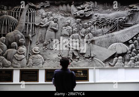 (140320) -- SEMARANG, March 20, 2014 (Xinhua) -- A tourist looks at a relief wall telling the story of Chinese navy explorer Zheng He in front of the Sam Poo Kong Temple, in Semarang, Central Java, Indonesia, March 20, 2014. Chinese navy explorer Zheng He who visited the Central Java Province s port city of Semarang 600 years ago, built a mosque and set up a Chinese Muslim community in the city. The mosque was later turned into a temple by Semarang residents, now known as Sam Poo Kong with a huge Zheng He statue in its front. (Xinhua/Zulkarnain) (djj) INDONESIA-CENTRAL JAVA-SAM POO KONG TEMPLE Stock Photo