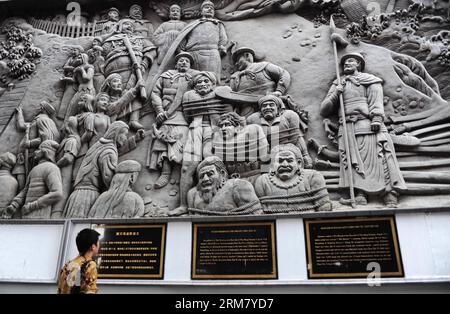 (140320) -- SEMARANG, March 20, 2014 (Xinhua) -- A tourist looks at a relief wall telling the story of Chinese navy explorer Zheng He in front of the Sam Poo Kong Temple, in Semarang, Central Java, Indonesia, March 20, 2014. Chinese navy explorer Zheng He who visited the Central Java Province s port city of Semarang 600 years ago, built a mosque and set up a Chinese Muslim community in the city. The mosque was later turned into a temple by Semarang residents, now known as Sam Poo Kong with a huge Zheng He statue in its front. (Xinhua/Zulkarnain) (djj) INDONESIA-CENTRAL JAVA-SAM POO KONG TEMPLE Stock Photo