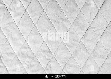 Quilted velours fabric background. White texture blanket or puffer jacket, stiched with diamond pattern, soft wrinkled surface, crupmed textile Stock Photo