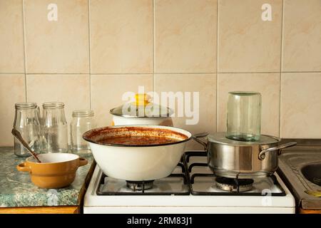 Cook homemade spicy adjika in a saucepan at home in the kitchen and next to the jars, cook spicy adjika, sauce Stock Photo
