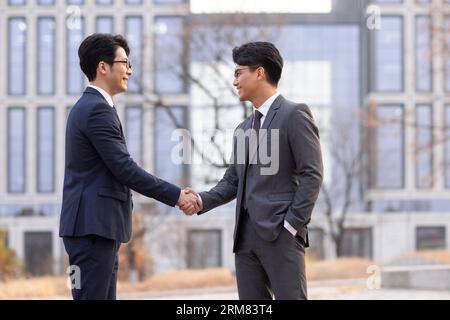 Confident businessmen shaking hands outdoors Stock Photo
