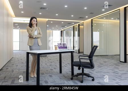 Confident businesswoman thinking in empty office Stock Photo