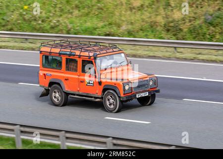 2003 Land Rover Defender 110 Td5 County Orange LCV Station Wagon Diesel 2495 cc travelling at speed on the M6 motorway in Greater Manchester, UK Stock Photo