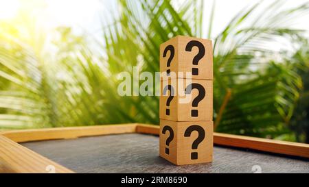Stack of three wooden cubes with question mark over nature background with sunlight with copy space Stock Photo