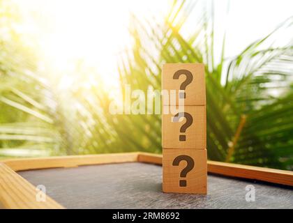 Stack of three wooden cubes with question mark over nature background with sunlight with copy space Stock Photo