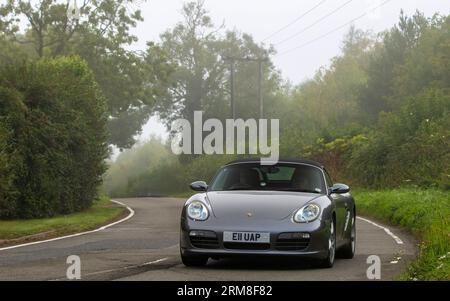 Whittlebury,Northants,UK -Aug 26th 2023: 2007 grey Porsche Boxster car travelling on an English country road on a damp and misty morning. Stock Photo