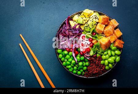 Vegan buddha bowl with red quinoa, fried tofu, avocado, edamame beans, green peas, radish, cabbage, pomegranate  and sesame seeds with soy sauce. Heal Stock Photo
