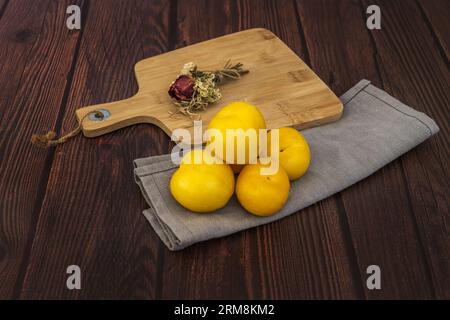 Still life of yellow plum on a gray canvas cloth and a bamboo table with a bouquet of dried flowers Stock Photo