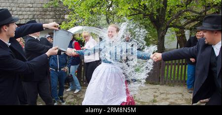 (140421) -- HOLLOKO, April 21, 2014 (Xinhua) -- Local men splash water at a girl as part of traditional Easter celebrations in Holloko, a village in northern Hungary, April 21, 2014. Local people from Holloko, which was inscribed on the World Heritage List, celebrate Easter with the traditional watering of the girls , a Hungarian tribal fertility ritual rooted in the area s pre-Christian past. (Xinhua/Attila Volgyi)(zhf) HUNGARY-HOLLOKO-EASTER MONDAY-CELEBRATIONS PUBLICATIONxNOTxINxCHN   April 21 2014 XINHUA Local Men Splash Water AT a Girl As Part of Traditional Easter celebrations in  a Vill Stock Photo