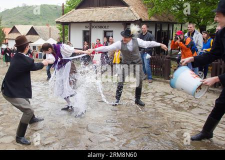 (140421) -- HOLLOKO, April 21, 2014 (Xinhua) -- Local men splash water at a girl as part of traditional Easter celebrations in Holloko, a village in northern Hungary, April 21, 2014. Local people from Holloko, which was inscribed on the World Heritage List, celebrate Easter with the traditional watering of the girls , a Hungarian tribal fertility ritual rooted in the area s pre-Christian past. (Xinhua/Attila Volgyi)(zhf) HUNGARY-HOLLOKO-EASTER MONDAY-CELEBRATIONS PUBLICATIONxNOTxINxCHN   April 21 2014 XINHUA Local Men Splash Water AT a Girl As Part of Traditional Easter celebrations in  a Vill Stock Photo