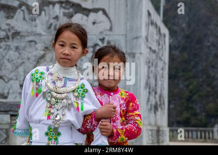 Mã Pí Lèng, Vietnam - January 28th 2020: Two Hmong girls wearing colorful traditional clothes, posing for a picture along the Ha Giang Loop road Stock Photo