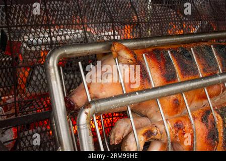 Close-up of a whole pig being roasted on an open charcoal fire. Preparation for a barbecue (BBQ) somewhere in France. Hi-res picture with copyspace if Stock Photo