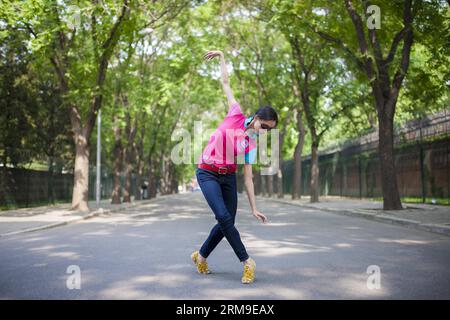 (140520) -- BEIJING, May 20, 2014 (Xinhua) -- Liu Lushi, a 22-year-old ballerina of the National Ballet of China, makes a ballet pose on a street in Beijing, capital of China, May 18, 2014. Before being able to present perfect performance in the spotlight, every member of the National Ballet of China has to undergo severe arduous training for years. Yet they chose to persevere in what they truely love. Years of toiling not only allows them good body shape, expertise and disposition, but also offers them a life-long goal that deserves pursuing. The glory on stage is only a small fraction of all Stock Photo